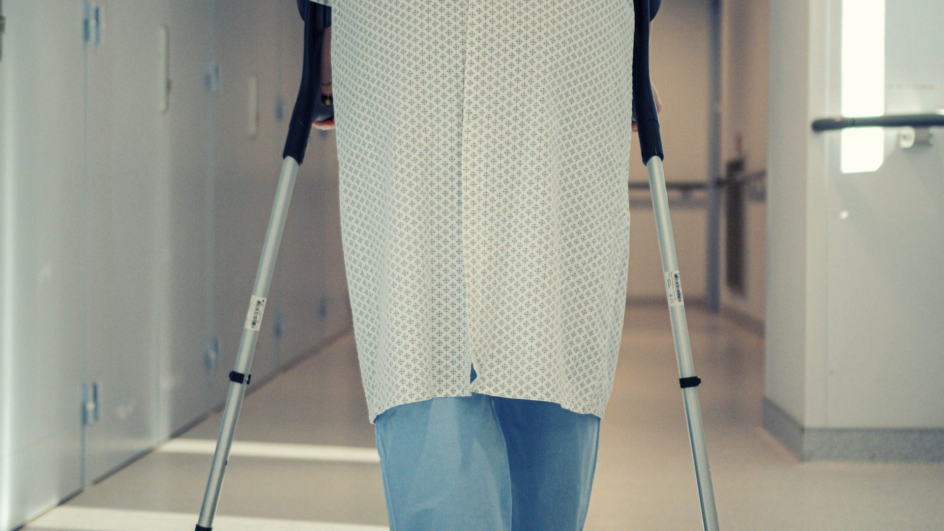 Patient walking with crutches in a hospital corridor